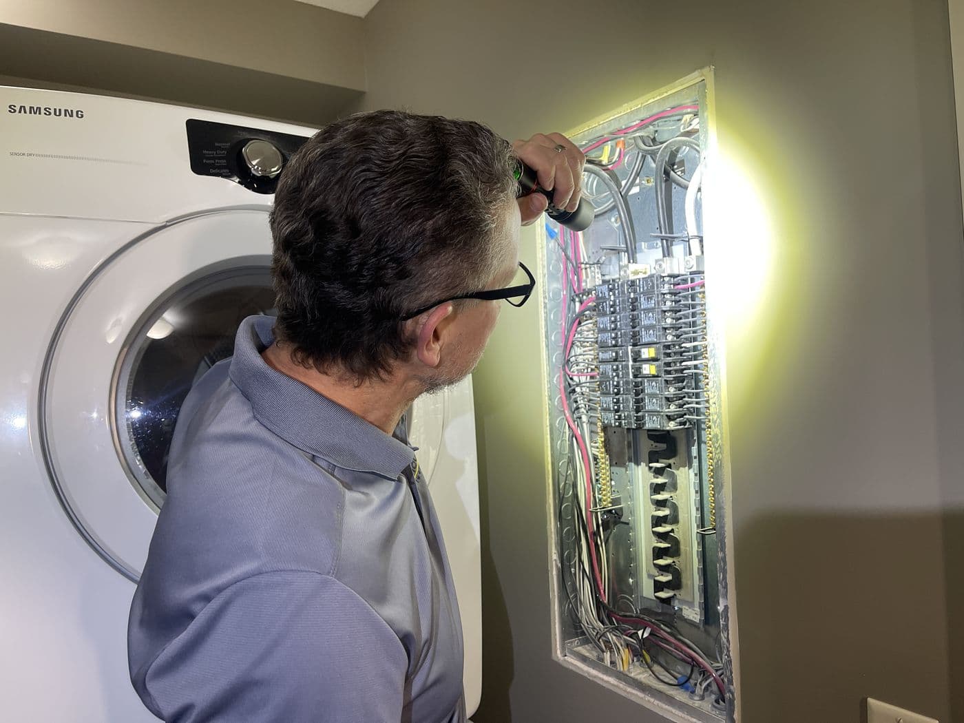 Kyle Dowdeswell inspecting an electrical panel in a laundry room