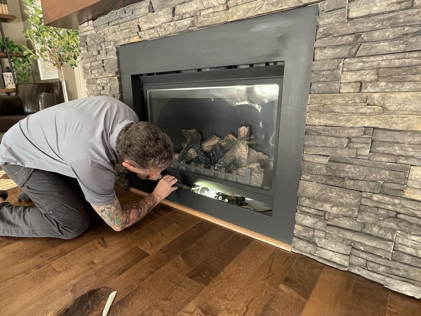 Kyle Dowdeswell inspecting a fireplace set in a stone wall