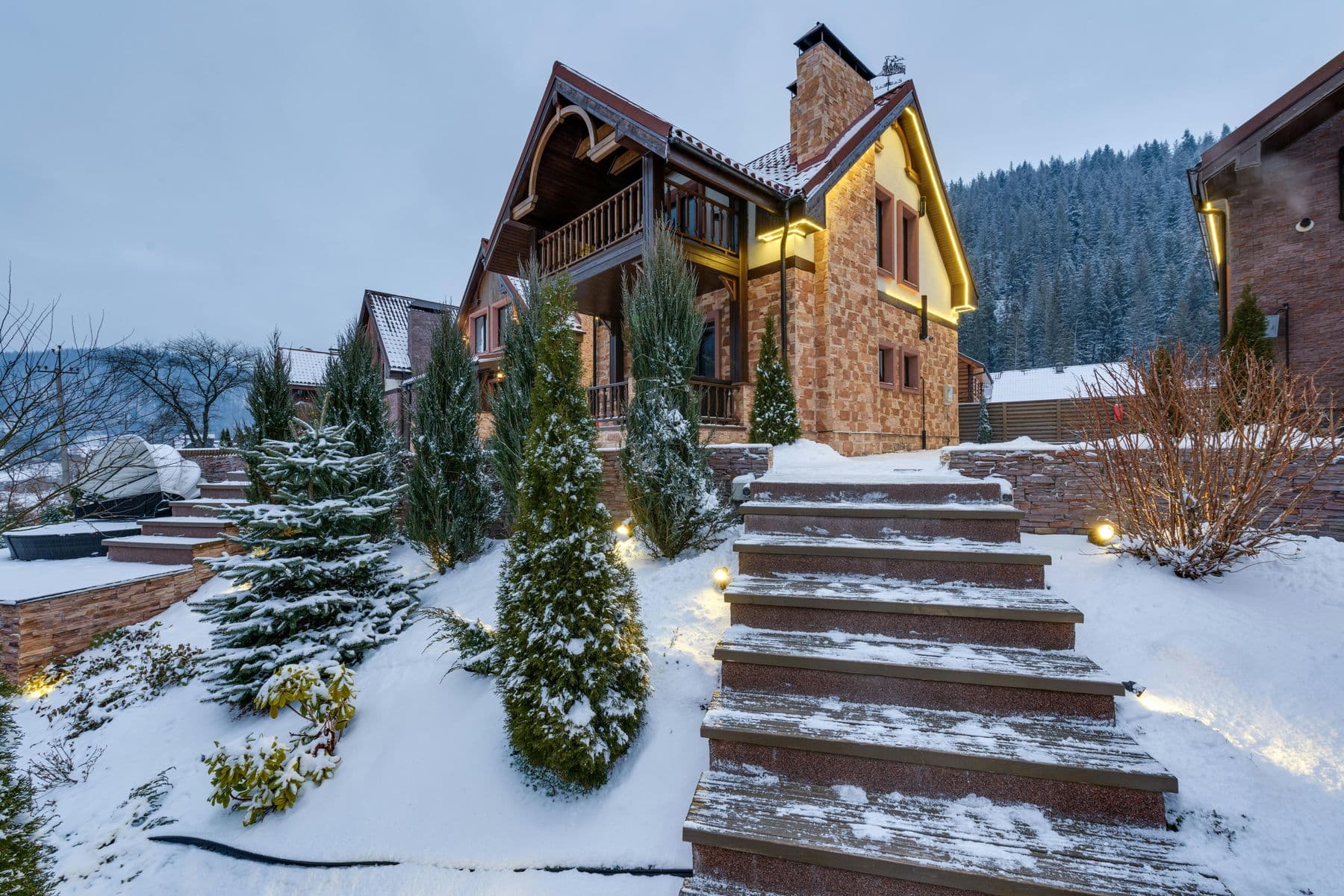 Mountain home with timber balconies and stone steps in winter